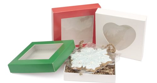 trzy kwadratowe pudełka na ciastka z okienkiem: białe, czerwone i zielone; w jednym pudełku widać pierniczek w kształcie śnieżynki